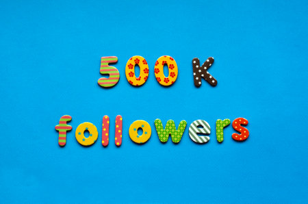 text 500 k followers from bright colored paper letters on blue paper backgroundの写真素材
