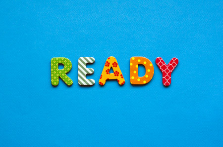 word ready from bright colored paper letters on blue paper backgroundの写真素材