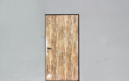 Background of a gray wall with closed wooden door.の写真素材