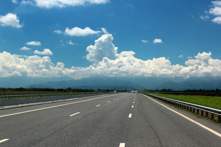 Highway and distant mountains in the clouds on horizonの写真素材