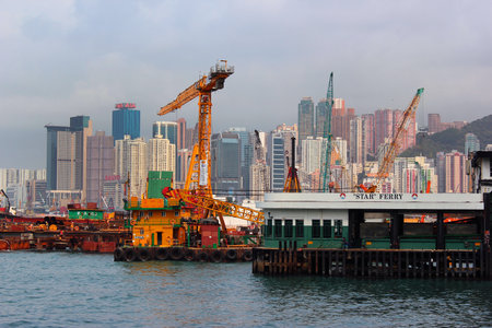 HONG KONG, MARCH 21, 2012: Cargo cranes and Wan Chai Star Ferry Terminal. Ferries connect the Hong Kong Island with Kowloon and Tsim Sha Tsui across Victoria Harbour.のeditorial素材