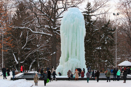 KHARKIV, UKRAINE - JANUARY 22, 2016: People taking pictures and having fun in front of the frozen fountain at Taras Shevchenko park. Unusually cold weather damaged the fountain and caused water leakage.のeditorial素材