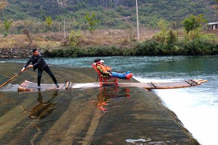 YANGSHUO, CHINA - MARCH 16, 2012: Girls going down the Yulong river on bamboo raft near Yangshuo town. Rafting is very popular attraction among tourists.のeditorial素材