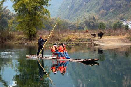 YANGSHUO, CHINA - MARCH 16, 2012: Girls going down the Yulong river on bamboo raft near Yangshuo town. Rafting is very popular attraction among tourists.のeditorial素材