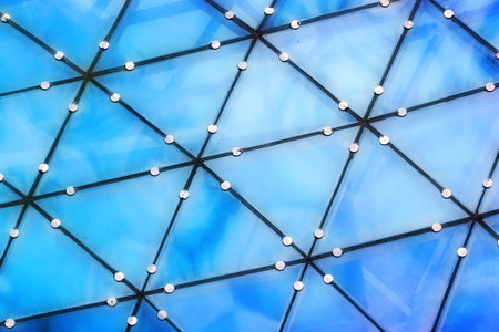 Blue reflections of clouds in glass trianles of transparent roof
