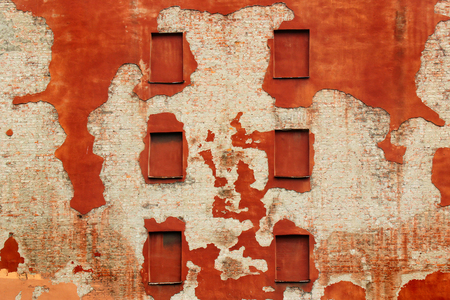 Boarded windows in old brick wall covered with red flaking plasterの写真素材
