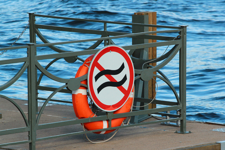 Life buoy on a pier with sign prohibiting usage during wavesの写真素材