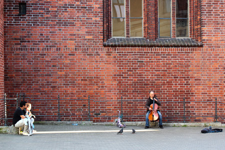 RIGA, LATVIA - JULY 10, 2017: Man plays cello near the Riga Dome Cathedral of Saint Mary in old town of Riga, famous for its pipe organ and acoustics.のeditorial素材