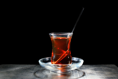 Hot tea in traditional turkish bardak glass, isolated on black backgroundの写真素材