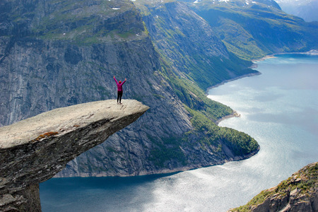 A woman stands on Trolltunga (Troll's Tongue), the cliff above the lake Ringedalsvatnet, a popular tourist destination in Hordaland county, Norway.の写真素材