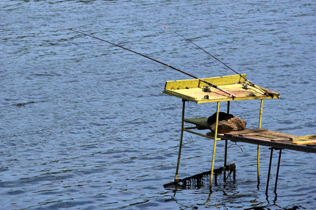 Old fishing tackle, rods with lines and reels. Angling equipment left on a self-made platform.の写真素材