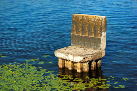 Old abandoned concrete support of a bridge looks like a chair in waterの写真素材