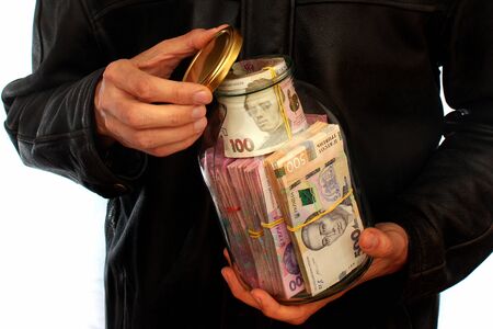 Man with glass jar full of hryvnia banknotes, the money of Ukraine. Concept of money deposited in a savings bank account.の写真素材