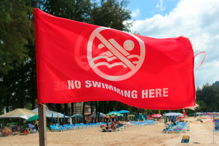 Phuket, Thailand - December 4, 2019: No swimming here sign on red flag at the Kamala Beach, Phuket.のeditorial素材