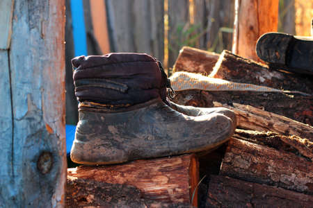 Old rubber boots on a pile of firewood, rural lifestyle conceptの写真素材