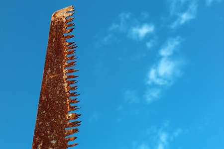 Teeth of old rusty handsaw isolated against blue skyの写真素材