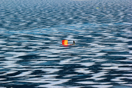 Bright orange fishing tent on a frozen lakeの写真素材