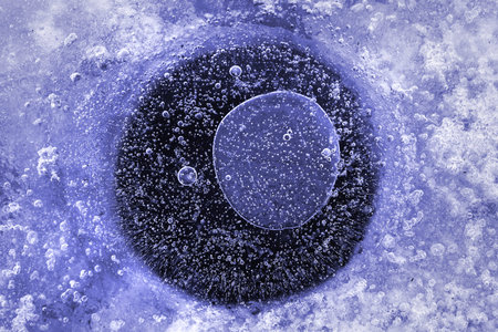 Air bubbles in ice, water hole in wintertime