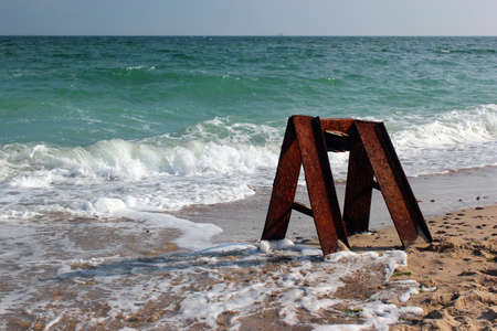 Old rusty abandoned bollard, steel beams and rails on a seashoreの写真素材