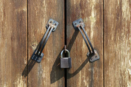 Two handles and padlock on a closed wooden doorの写真素材