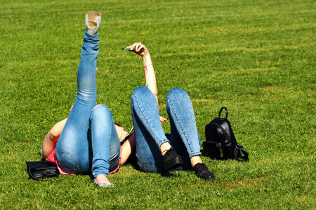 Two young woman taking a selfie on a green lawn