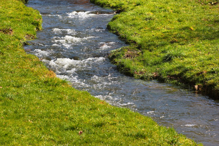 Little brook flowing in green meadows, spring natural backgroundの写真素材