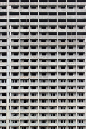 Unfinished concrete apartment building with repetitive window patternの写真素材