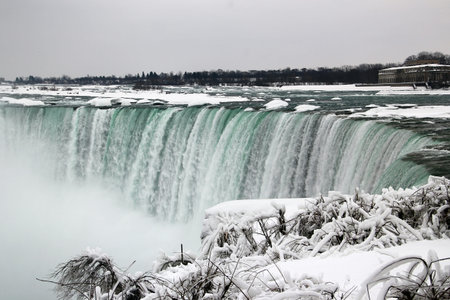 Winter panorama of Niagara Falls with turquoise cascade, icy river and snow covered shorelineの写真素材