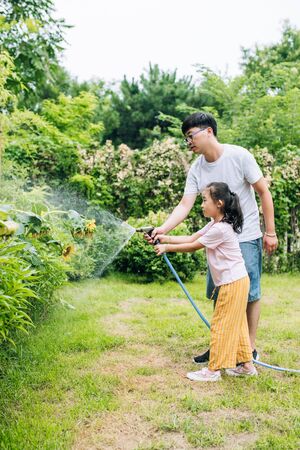 Father and girl watering plants and lawns in the backyardの写真素材
