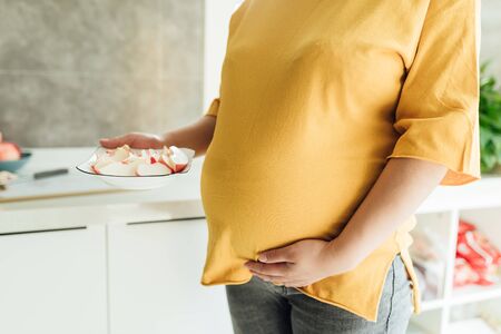 A pregnant woman of more than eight months is cutting fruitの写真素材