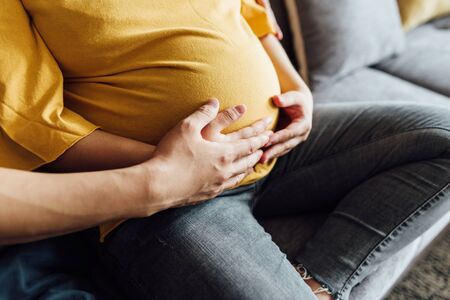 The couple's hands are touching the belly of the pregnant womanの写真素材