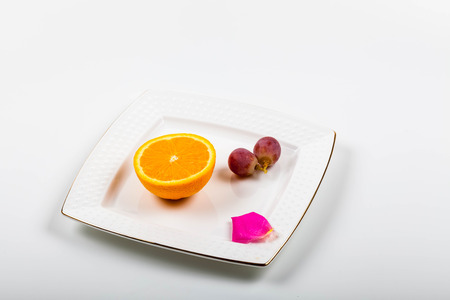 Fruits on a plate with pink petalの写真素材