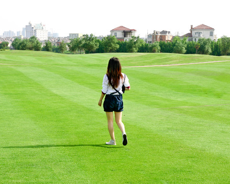 Young Asian businesswoman standing on the lawn holding a computer, leaving the backの写真素材