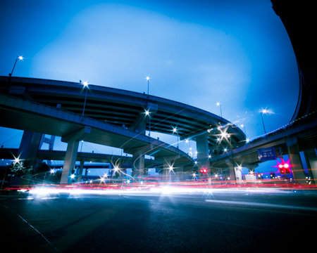 Freeway in night with cars light in modern city.