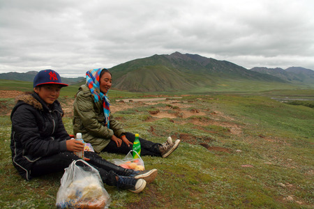 GUOLUO, CHINA - JULY 26: Mother and daughter sit on the grassland and taking a rest.のeditorial素材