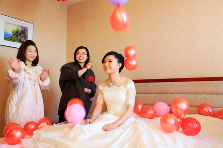LUANNAN COUNTY - DECEMBER 29: Friends throw red balloons to the bride's head, bless bride, traditional customs in chinese wedding, on december 29, 2013, Luannan County, Hebei Province, China.のeditorial素材