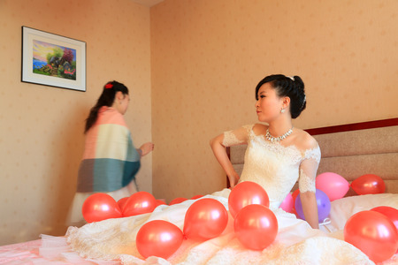 LUANNAN COUNTY - DECEMBER 29: The bride sat on the bed, waiting for the arrival of the groom, traditional customs in chinese wedding, on december 29, 2013, Luannan County, Hebei Province, China.のeditorial素材