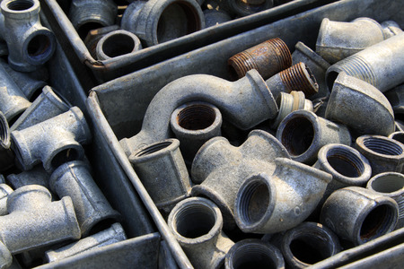 Metal plumbing pipe fittings piled up in the box  in a marketの写真素材