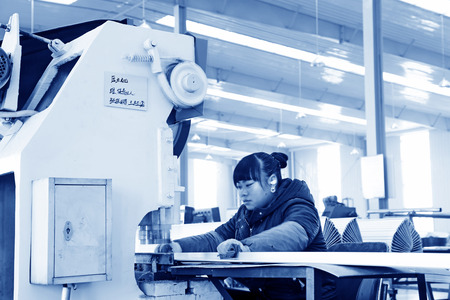 TANGSHAN - DECEMBER 22: The worker in operating machinery on the production line, in a solar equipment production workshop on december 22, 2013, tangshan, china.のeditorial素材
