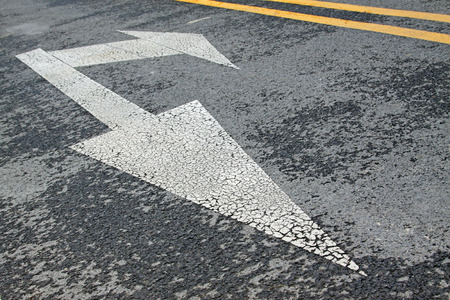 white arrow symbol on asphalt road, closeup of photoの写真素材