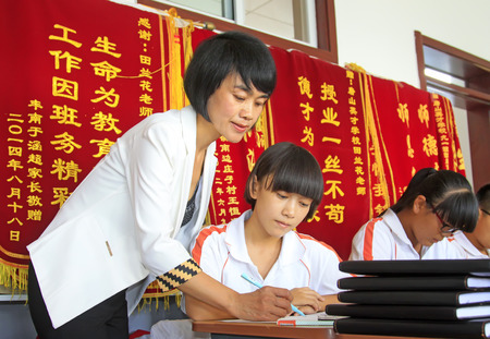 LUANNAN COUNTY - SEPTEMBER 3: A female teachers guiding students to learn in classroom, on september 3, 2014, Luannan County, Hebei Province, Chinaのeditorial素材