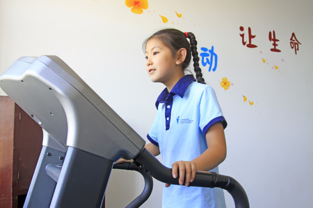 LUANNAN COUNTY - SEPTEMBER 3: little girl doing exercise on treadmill in a school, on september 3, 2014, Luannan County, Hebei Province, Chinaのeditorial素材