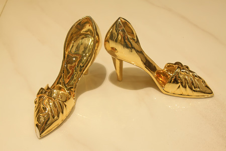 Aureate high-heeled shoes on the ceramic tile, closeup of photoの写真素材