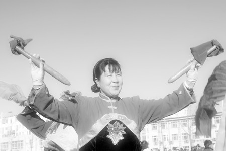 LUANNAN COUNTY - FEBRUARY 9: Woman holding pairs of wooden stick performing yangko dance in the street, during the Chinese Lunar New Year, February 9, 2014, Luannan County, Hebei Province, China.のeditorial素材