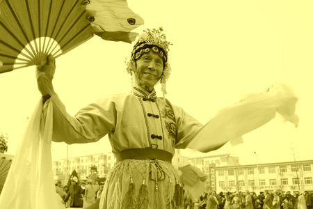 LUANNAN COUNTY - FEBRUARY 15: Old man wearing colorful clothes, performing yangko dance in the street, during the Chinese Lunar New Year, February 15, 2014, Luannan County, Hebei Province, China.のeditorial素材