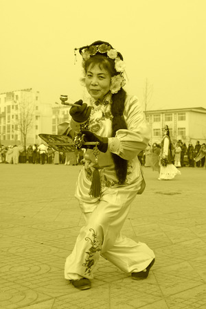 LUANNAN COUNTY - FEBRUARY 15: Woman holding pairs of wooden stick performing yangko dance in the street, during the Chinese Lunar New Year, February 15, 2014, Luannan County, Hebei Province, China.のeditorial素材