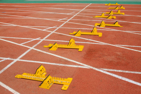 yellow starting block and athletes, closeup of photo