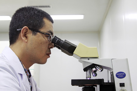 Luannan - June 29: doctor in the microscope to observe the pathological section, on June 29, 2015, luannan county, hebei province, Chinaのeditorial素材