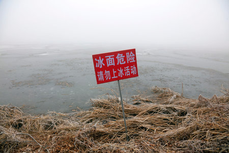 words "ice surface danger" on the board by shoreの写真素材
