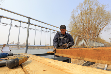 Luannan County - March 26, 2018: workers are processing wood planks in the outdoors, Luannan County, Hebei Province, Chinaのeditorial素材